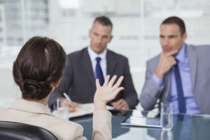 Brown haired woman talking to her interviewers in bright office